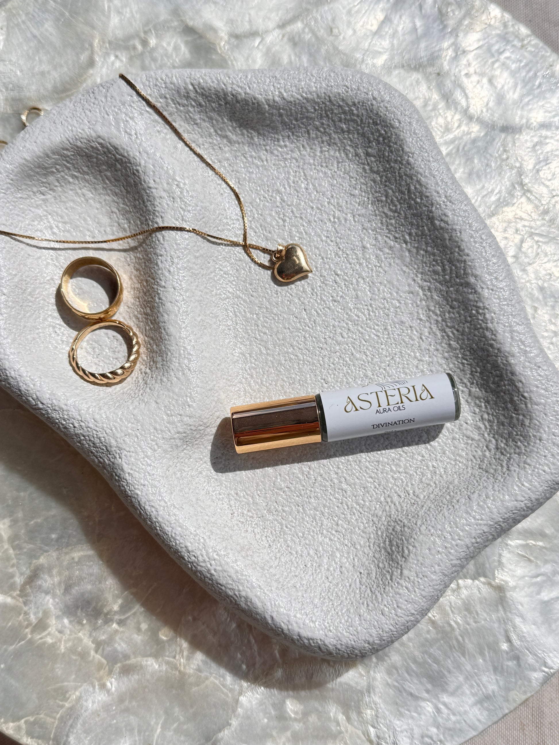 Roll-on bottle asteria aura oil and jewelry on a textured stone surface