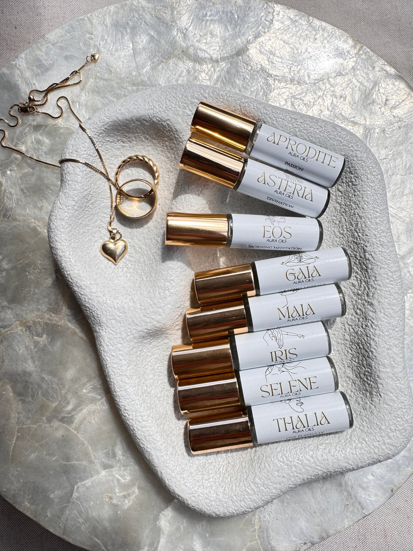 Roll-on bottles aura oil collection and jewelry on a textured stone surface