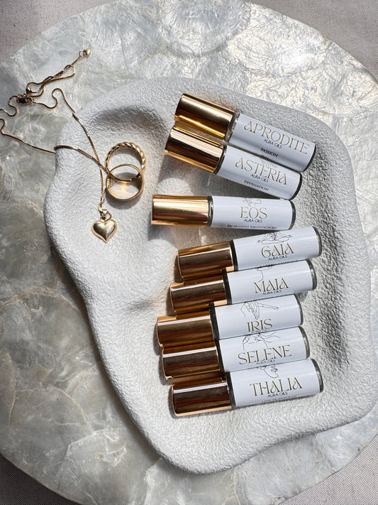 Roll-on bottles aura oil collection and jewelry on a textured stone surface